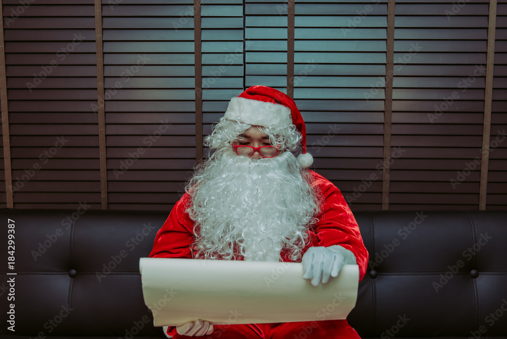 Fototapeta premium Santa Claus using a magnifying glass to look at the address of the children to bring gifts to send tonight.