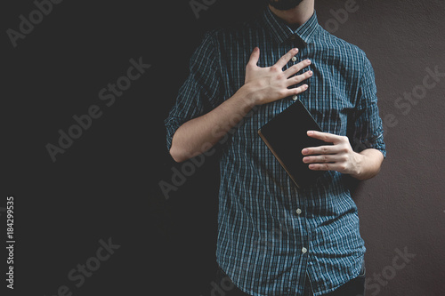Man holding Holy bible. Prayer concept for faith spirituality and religion gray background