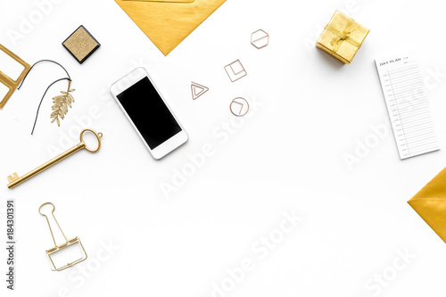 Office desk in trendy gold color. Glittering stationery near cell phone on white background top view copyspace