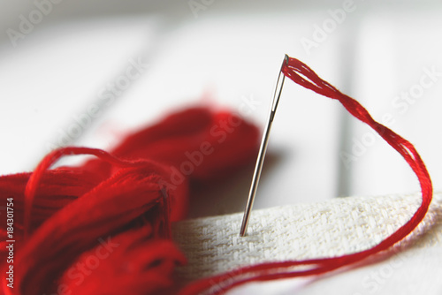 Needle in canvas with red thread for embroidery. Embroidery macro close up. View from above. Free copy space.