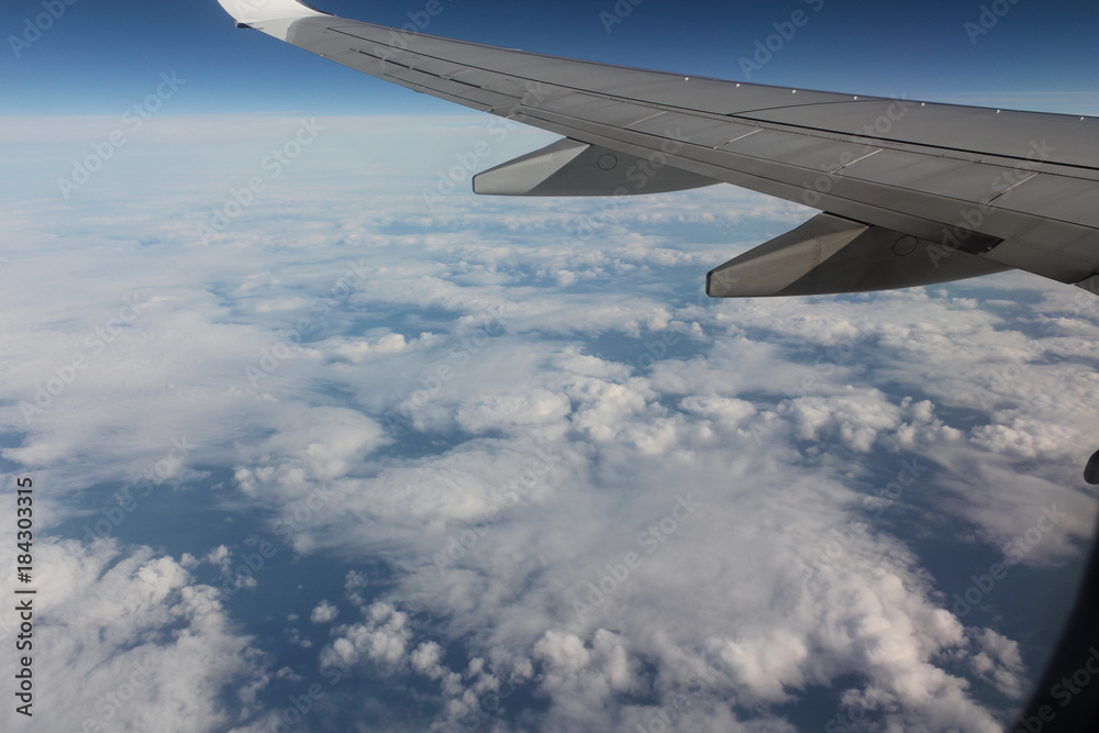  A passenger plane wing against a blue sky and white clouds