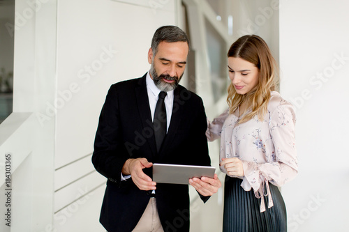 Middle-aged businessman and young businesswoman with tablet in offfice