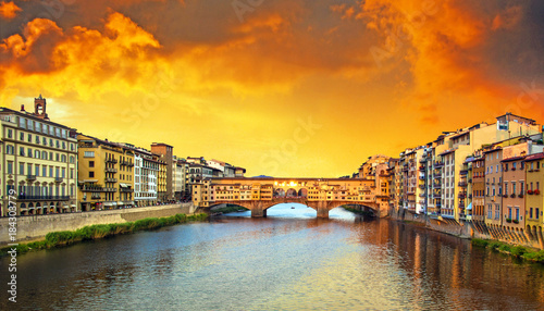 Beautiful city view with the famous medieval stone bridge Ponte Vecchio over the Arno river in Florence, Italy at sunset. Place of pilgrimage for tourists.