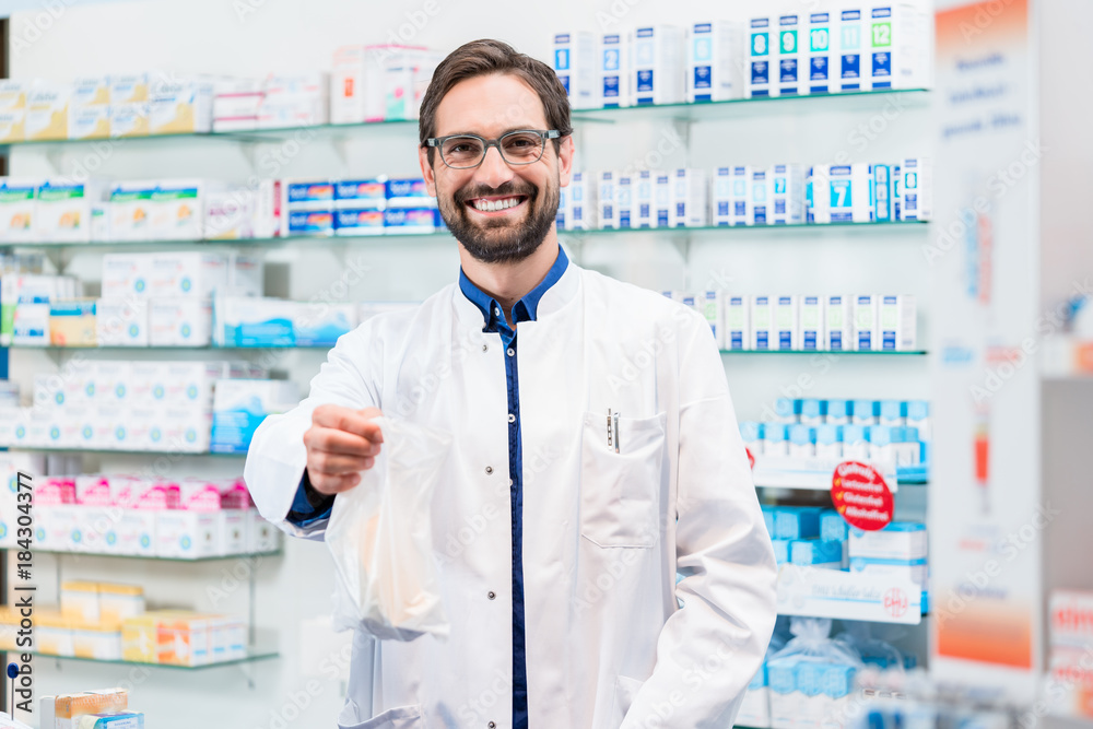 Pharmacist in pharmacy selling bag of pharmaceuticals