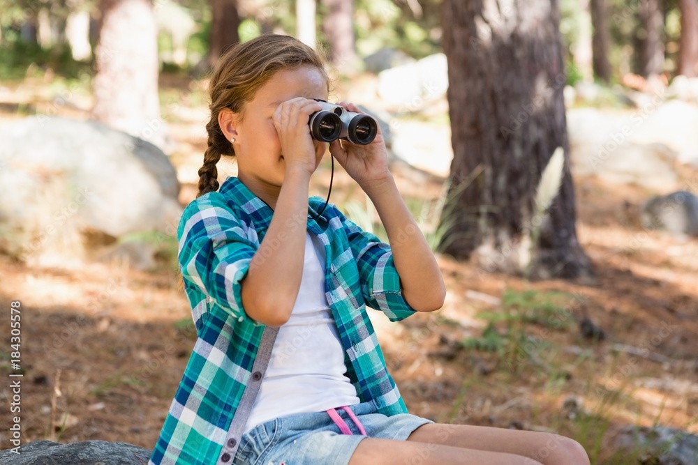 Girl looking through binoculars in the forest