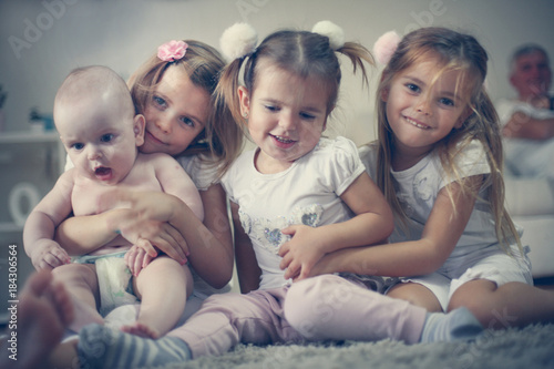 Little baby brother with sisters poses to camera.