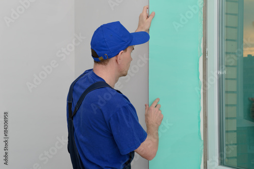 worker in uniform installs a plastic sandwich panel on the slopes of the window