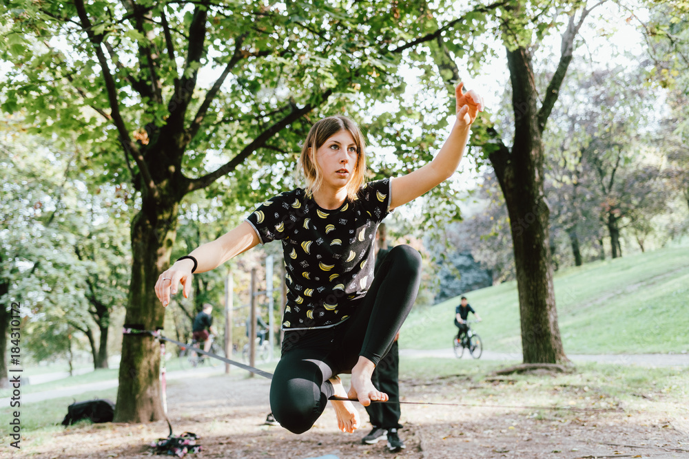 Φωτογραφία Woman balancing a tightrope or slackline outdoor in a city park in autumn - slac