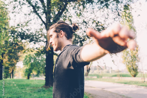 young man athlete stretching outdoor in a park - sport, training, active concept