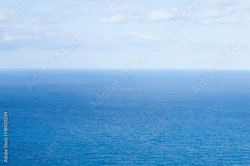 Cloudy blue sky over Mediterranean sea surface on a bright sunny day