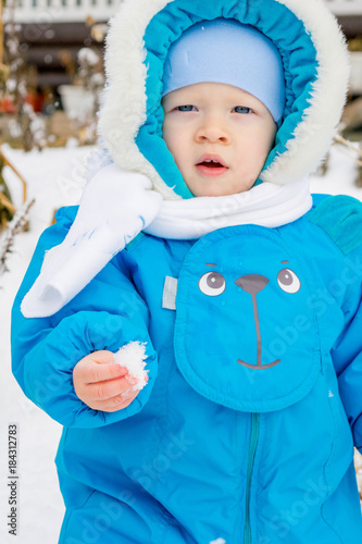 Baby boy surprised with first snow holding snow at his hand
