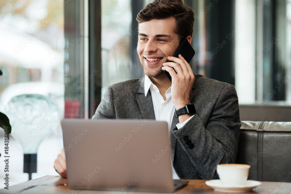 Smiling business man sitting by the table in cafe Smiling business man sitting by the table in cafe
