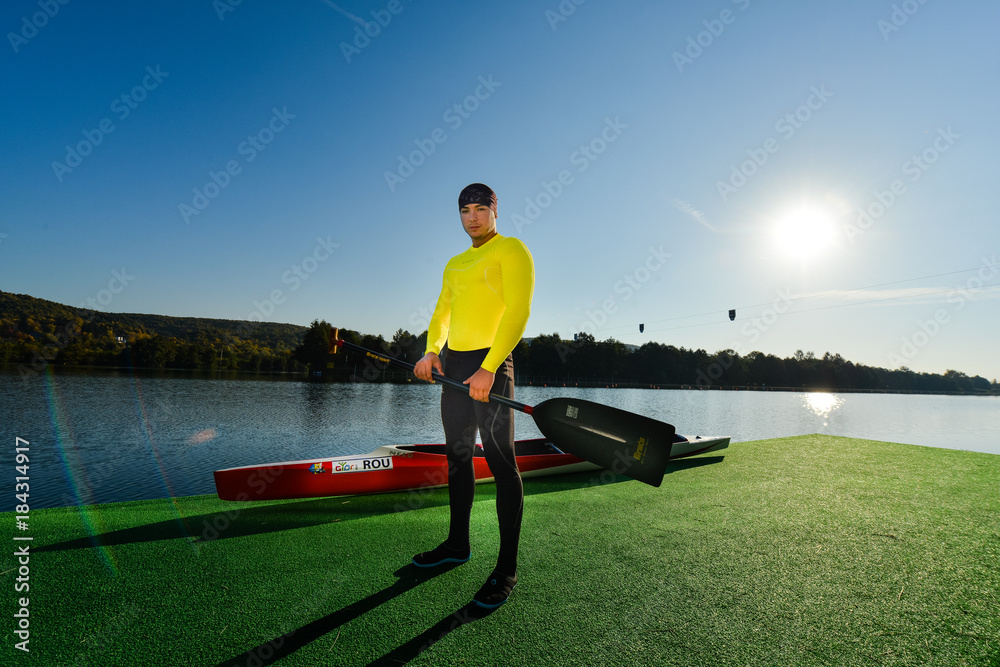 Naklejka premium Strong young man with his kayak on a sunny day on a lake. 