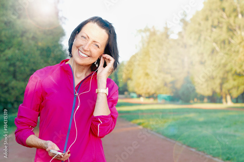 Mature woman listen music before or after jog in the park