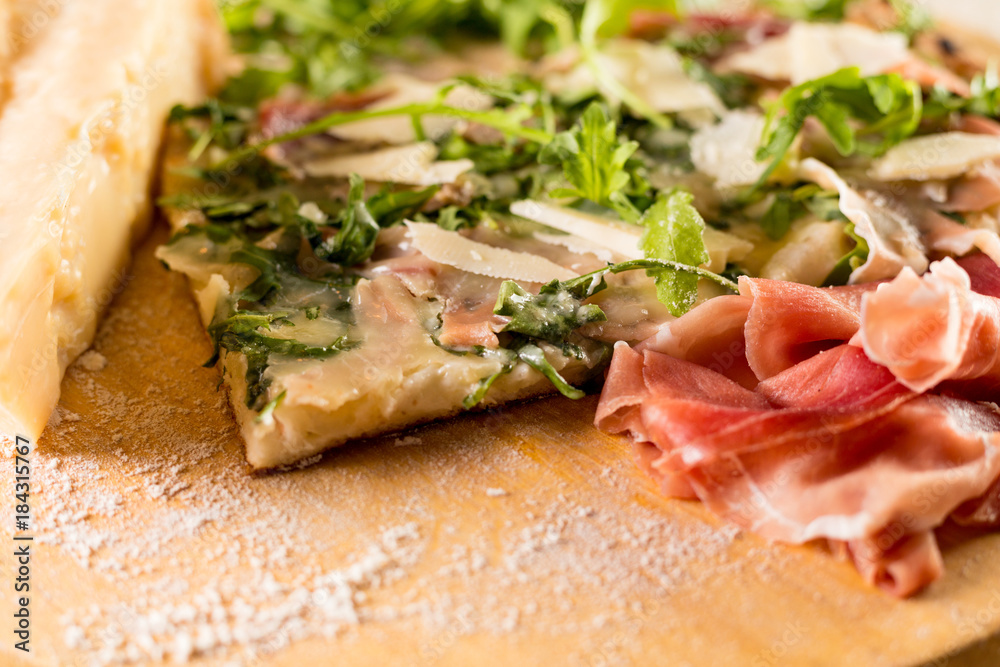 Pizza with Parma ham and cheese shavings on bed of rocket salad Pizza with Parma ham and cheese shavings on bed of rocket salad