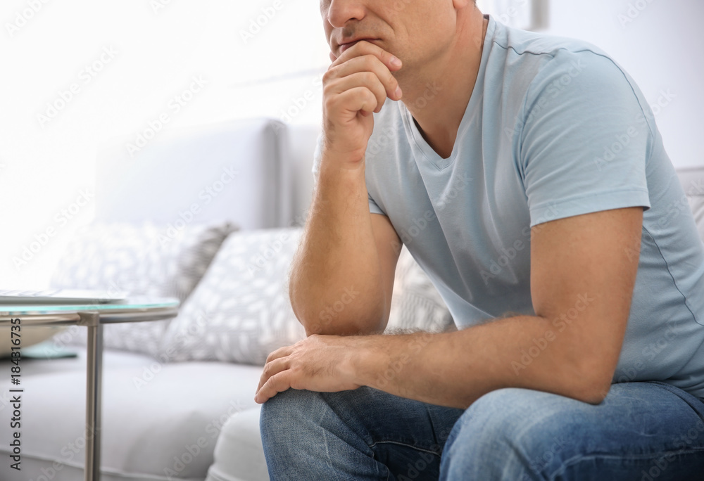 Thoughtful mature man sitting on sofa at home Thoughtful mature man sitting on sofa at home