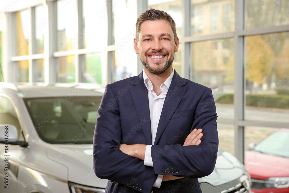 Handsome car salesman in dealership centre