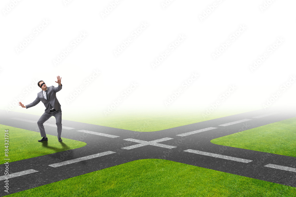 Young businessman at crossroads in uncertainty concept Young businessman at crossroads in uncertainty concept