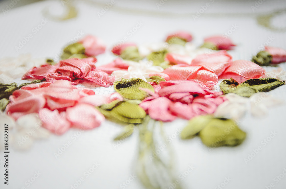 Beautiful flowers embroidered ribbon. Needlework, handicraft. Close-up, selective focus.