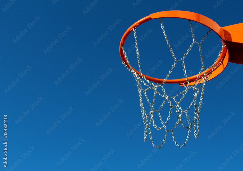 Orange basketball rim (hoop) and chain metal net against blue sky