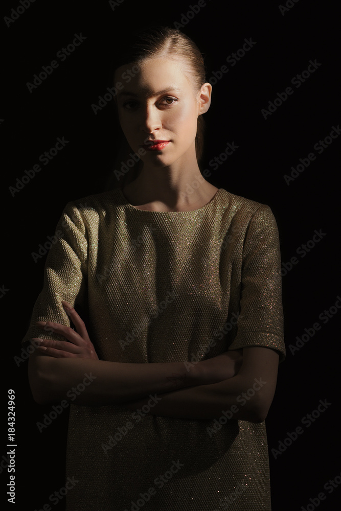 Low key portrait of girl with crossed hands and half lit face