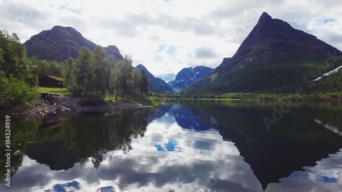 Drone flying through Norways most beautiful mountain valley. Lake reflecting the surreal landscape. Establishing intro shot. photo