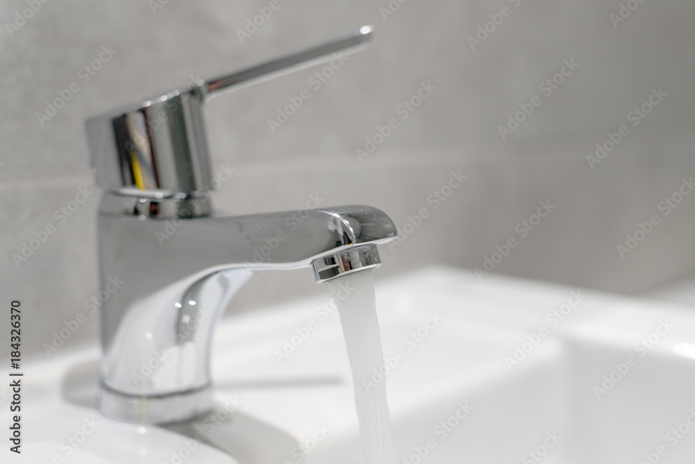 Home water faucet closeup, flow open spilling water into the drain