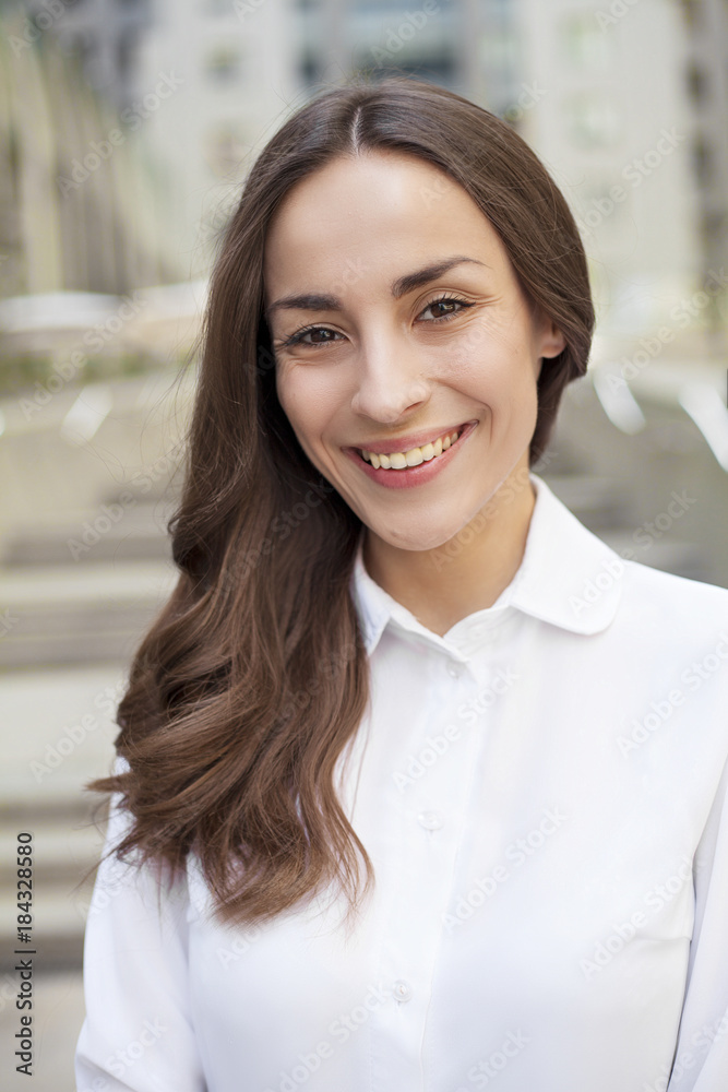 Portrait of a confident modern business woman with beautiful lush hair on the background of an office center in the city and looks on camera. Portrait of a confident modern business woman with beautiful lush hair on the background of an office center in the city and looks on camera.