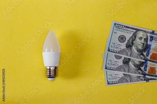 LED lamp on yellow background and dollas. photo