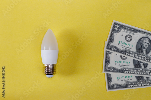 LED lamp on yellow background and dollas. photo