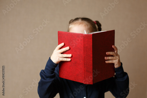 Beautiful baby covering her face with a book.