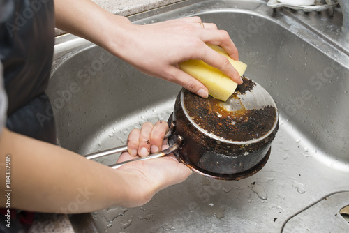 鍋の焦げ付きを磨く女性の手
