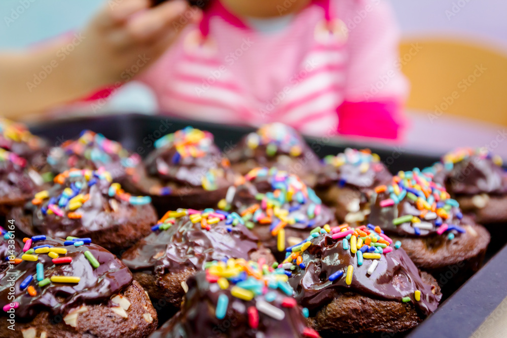 Portrait of sweet little child eating cake, decorated muffins