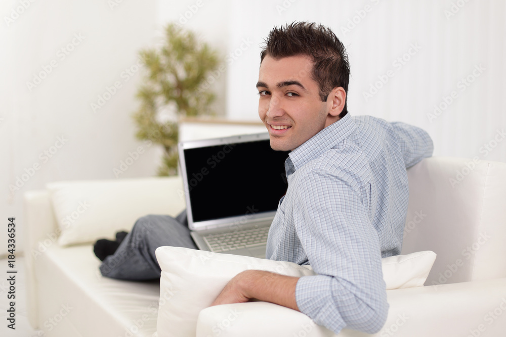 Handsome man is using a laptop, looking at camera and smiling Handsome man is using a laptop, looking at camera and smiling