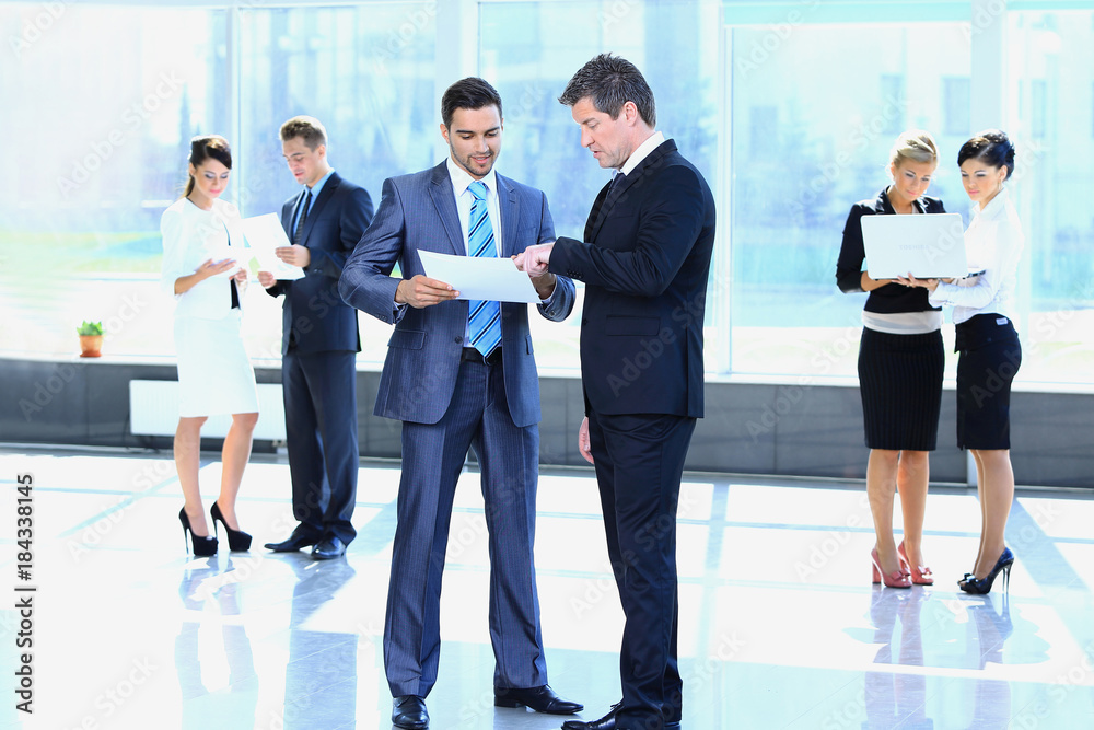 Fototapeta premium employees discuss working papers, standing in the lobby