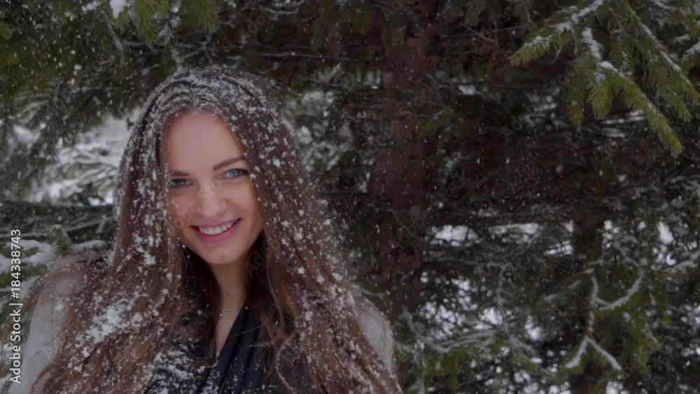 Snowflakes Falling on Beautiful Girl`s Face and long hair in Slow Motion. Portrait of young beautiful woman over snowy background. snow falling on her hair. Slow motion. It is snowing. outdoors. She Snowflakes Falling on Beautiful Girl`s Face and long hair in Slow Motion. Portrait of young beautiful woman over snowy background. snow falling on her hair. Slow motion. It is snowing. outdoors. She