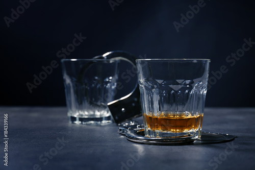 Glasses with handcuffs on dark background. Alcohol dependence concept