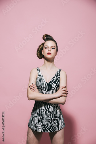Girl in stylish vintage dress on pink background.