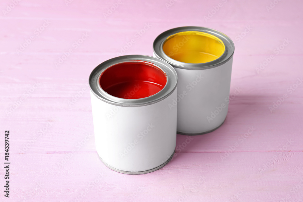 Tin cans with bright red and yellow paint on color background Tin cans with bright red and yellow paint on color background