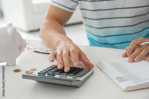 Young man counting taxes at table, closeup