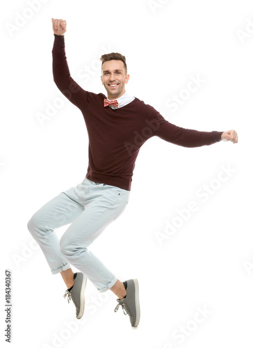 Handsome young man in bow tie jumping on white background
