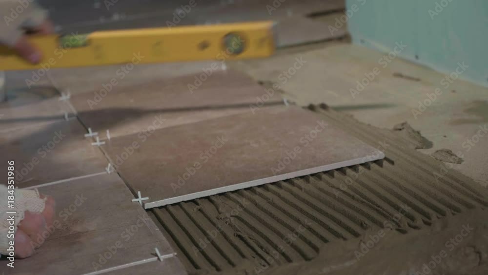 Professional worker laying tiles on floor Professional worker laying tiles on floor