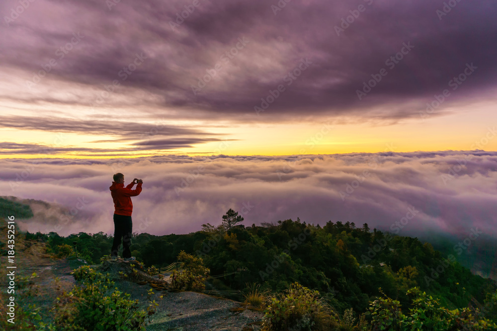 Silhouette of male photographer or traveler taking a photograph sunrise landscape on mountain top at Doi Inthanon National Park, Chiang Mai Province, Thailand