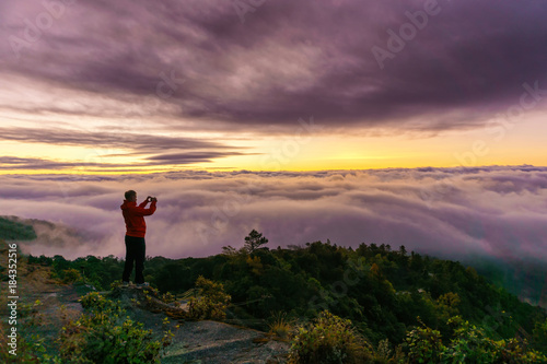Silhouette of male photographer or traveler taking a photograph sunrise landscape on mountain top at Doi Inthanon National Park  Chiang Mai Province  Thailand