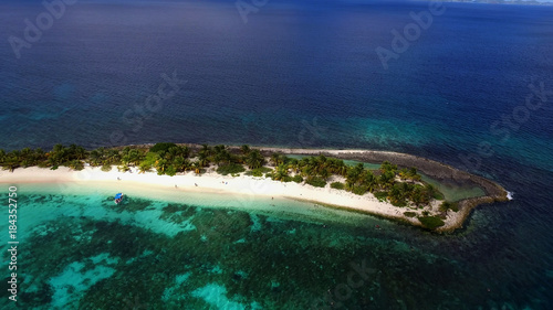 Top view aerial photo from flying drone of  tropical island in open sea. Small beach with turquoise water.