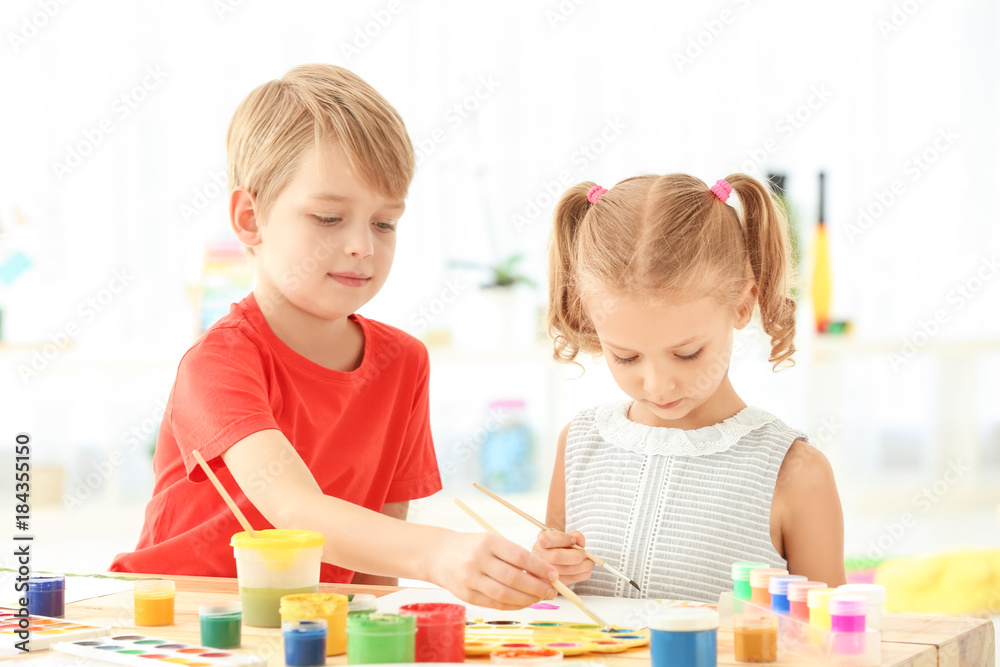 Cute children painting pictures at table indoors Cute children painting pictures at table indoors