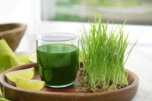 Plate with glass of wheat grass juice on table photo