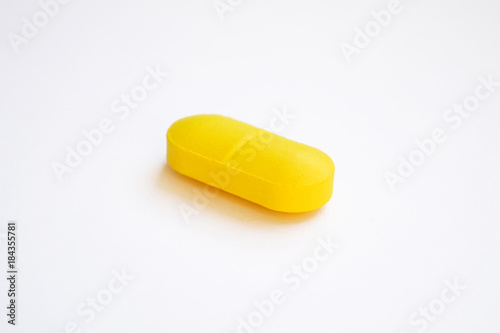 one yellow pill on white background
