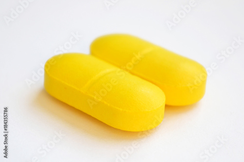 two yellow pills on white background