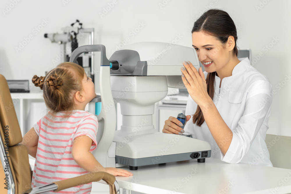 Ophthalmologist measuring intraocular pressure of little child in clinic Ophthalmologist measuring intraocular pressure of little child in clinic